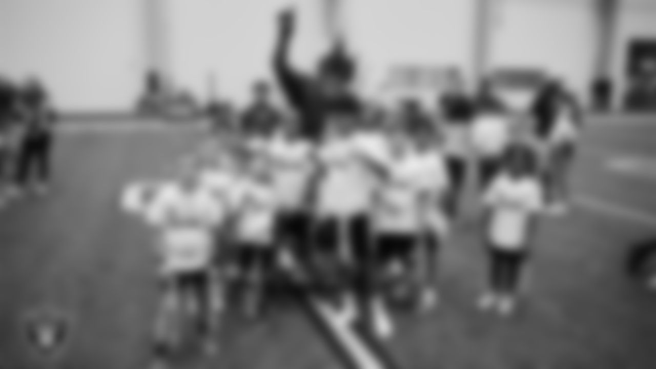Raider Rusher poses for a photo with athletes at a skills camp during Play Football Day at Intermountain Health Performance Center.