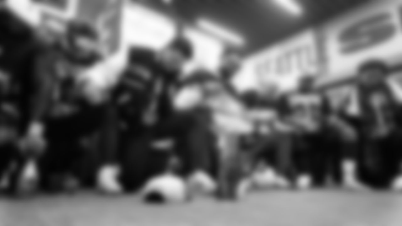 Back in the locker room, the Seahawks kneel in prayer after the game, with the Lombardi Trophy front and center.