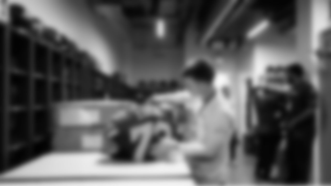 Doug DeKerchove Jr, a member of the team's equipment staff, readies the pads and jersey of Abraham Lucas in preparation for the game.