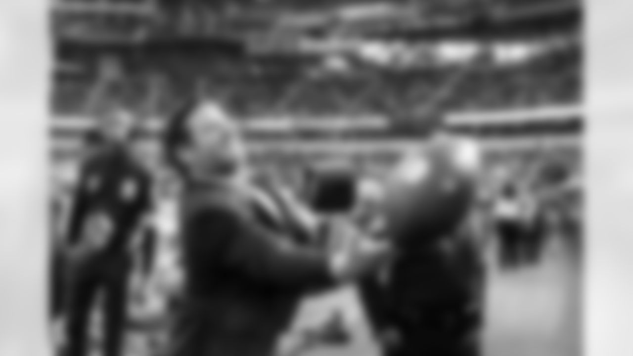 Seahawks president of football operations/general manager John Schneider tosses a football up to a young Seahawks fan sitting behind the team's bench before the game.