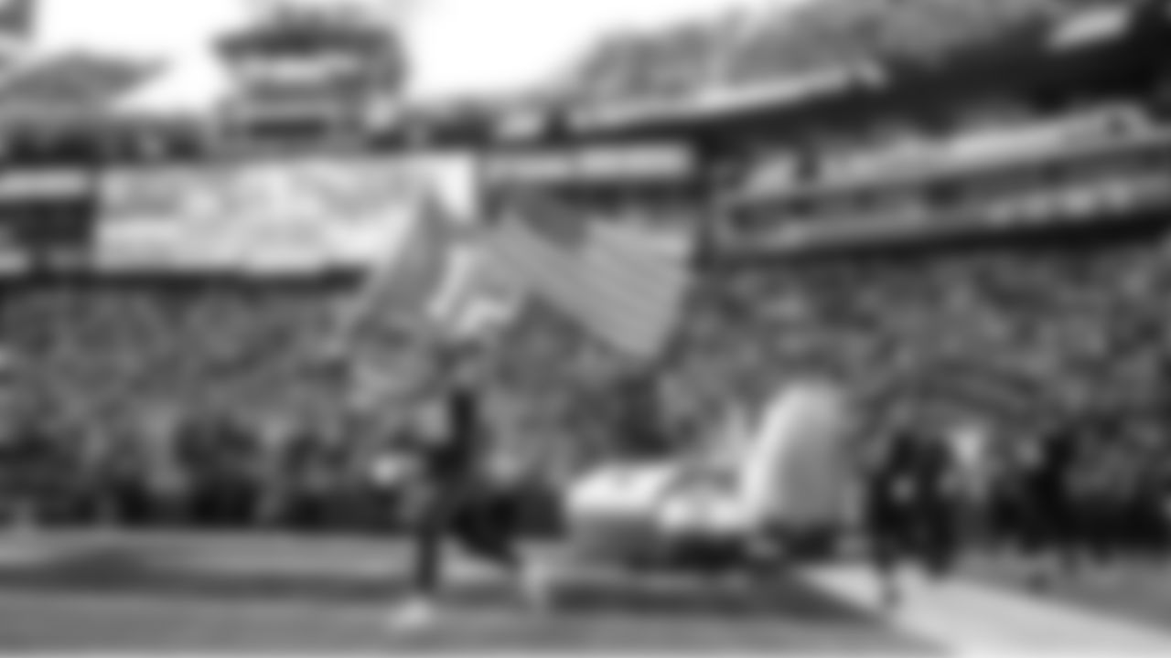 Seahawks tight end Brady Russell leads the team out of the tunnel holding both a 12 flag and a U.S. flag on Salute to Service Day.