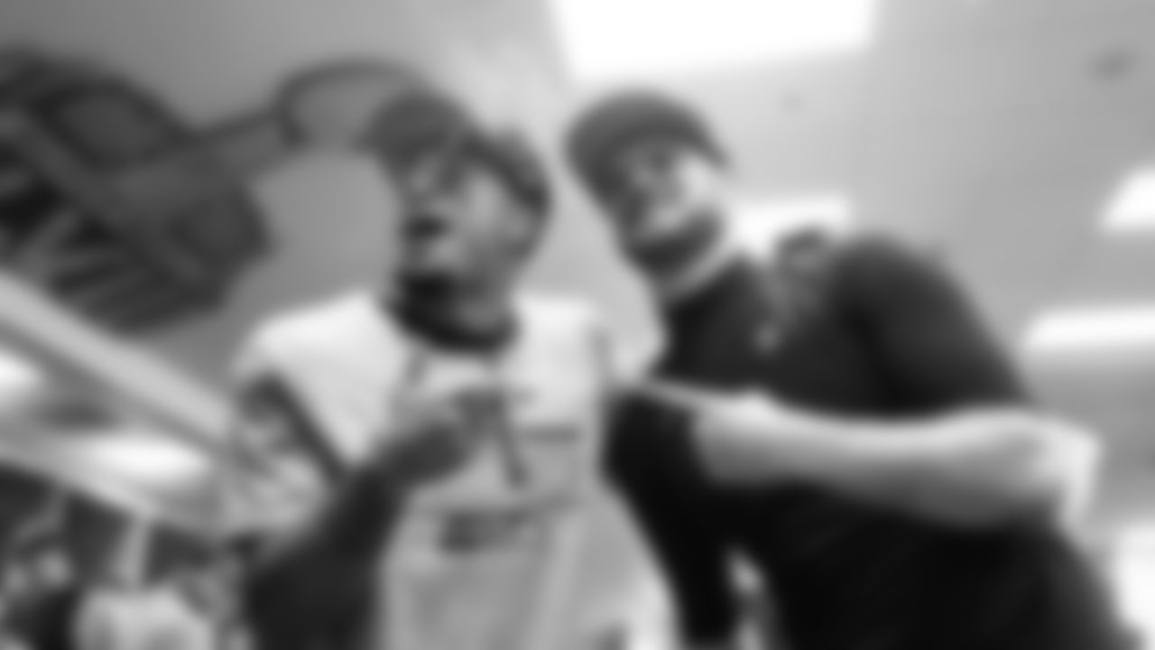 In the locker room, receiver Jaxon Smith-Njigba and quarterback Sam Darnold celebrate.