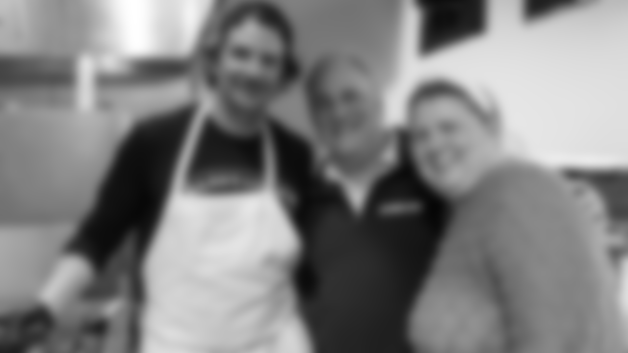 Bradley Cooper stops cooking for a photo with Defensive Coordinator Vic Fangio and Chief of Staff Katie David.